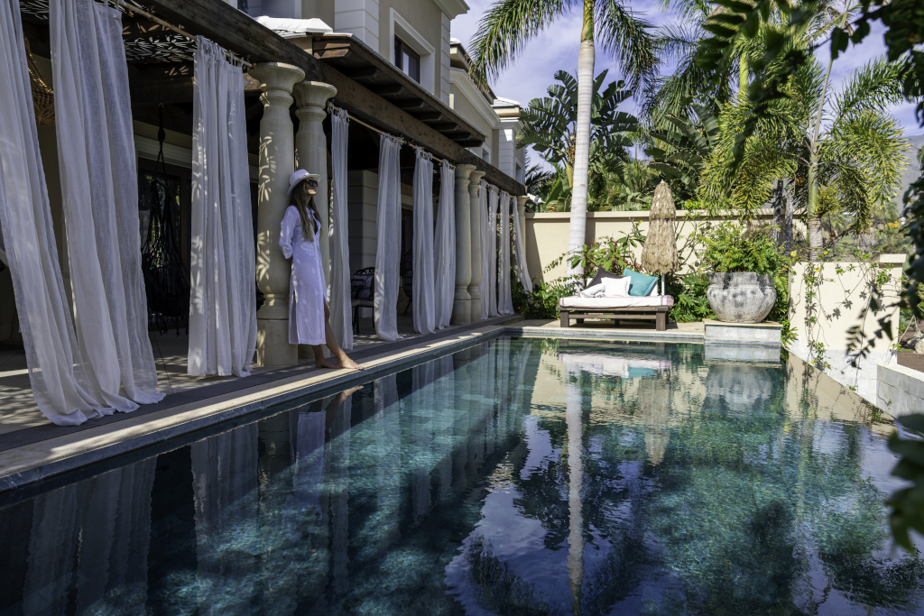 A woman in a white dress by a pool with palm trees in Tenerife.