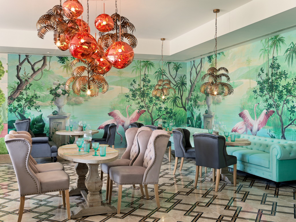 Dining area with elegant chairs, tropical mural, and colorful chandeliers in Tenerife.