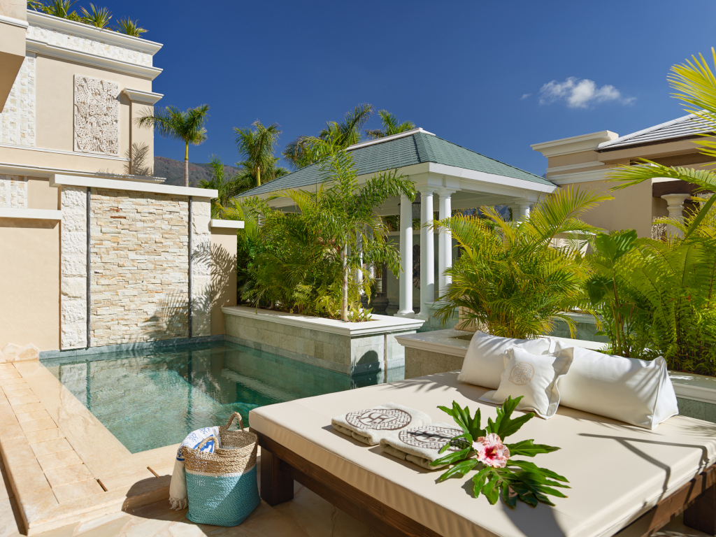 Luxurious poolside daybed surrounded by palm trees in Tenerife.