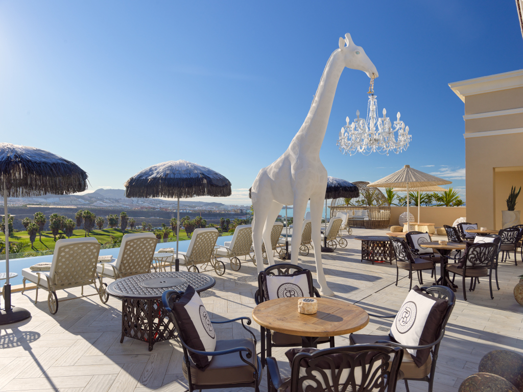Terrace with giraffe sculpture and chandeliers in Tenerife resort.