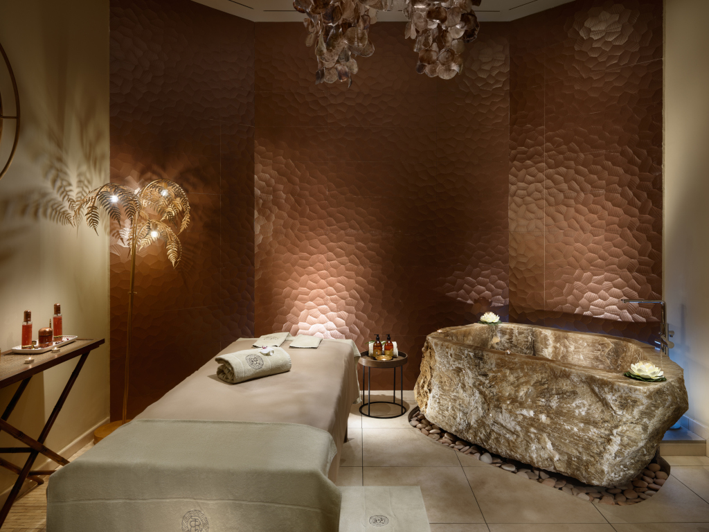 Spa room in Tenerife with a massage table, stone bathtub and ambient lighting.