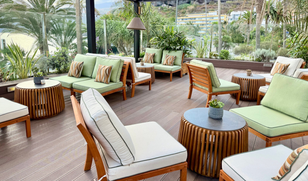Outdoor seating area with green cushions and wooden tables in Tenerife.