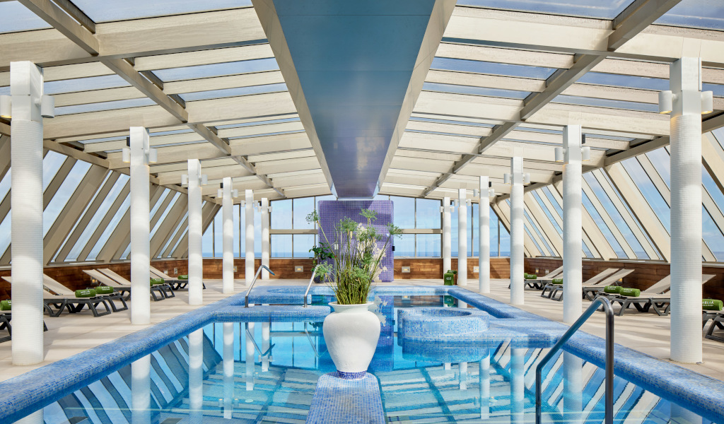 Indoor pool with lounge chairs under a glass roof in Tenerife.