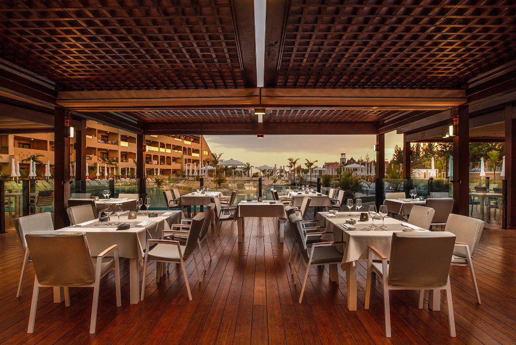 Outdoor restaurant seating with set tables and chairs at sunset in Tenerife.
