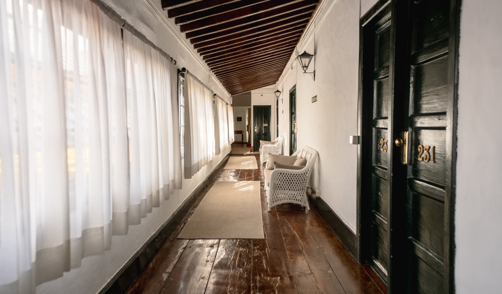 Hallway with wicker chairs, wooden doors numbered 23 and 231, in a Tenerife guesthouse.