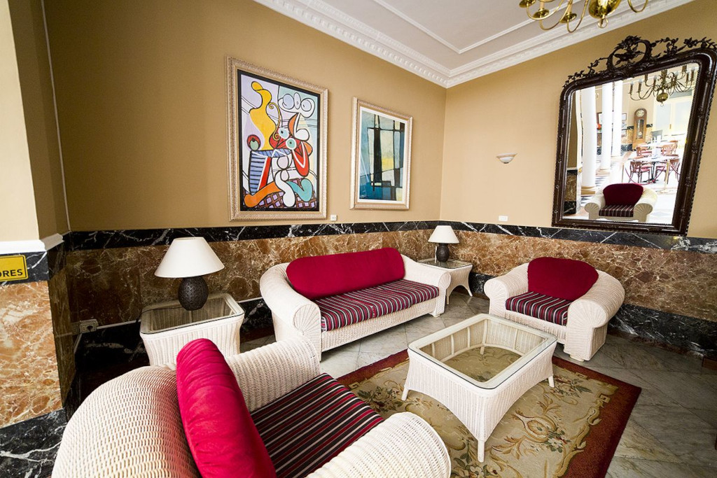 Wicker furniture in lounge area with paintings and a large mirror in Tenerife.