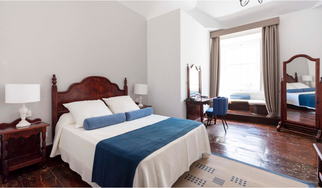 Bedroom with wooden floor, bed, nightstands, and window in Tenerife room.
