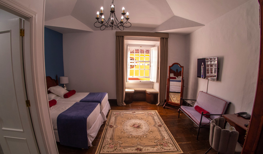 A cozy hotel room in Tenerife with twin beds, a window view, and wall-mounted TV.