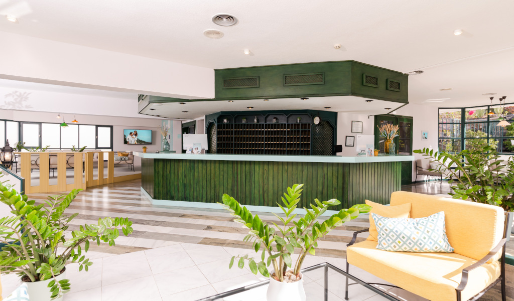 Hotel lobby with green reception desk, plants, and seating area in Tenerife.