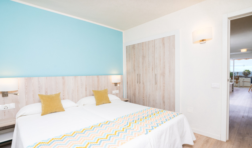 Two single beds in a Tenerife hotel room with sea view through open door.