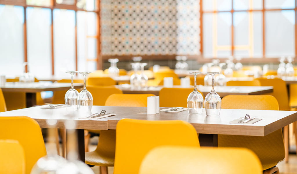 Dining tables set with glassware and cutlery in a bright, modern restaurant in Tenerife.