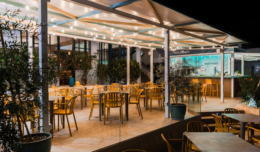 Outdoor dining area at Guacamayo restaurant in Tenerife, with empty chairs and tables.