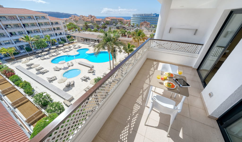 Balcony with breakfast overlooking pools and resort in Tenerife.