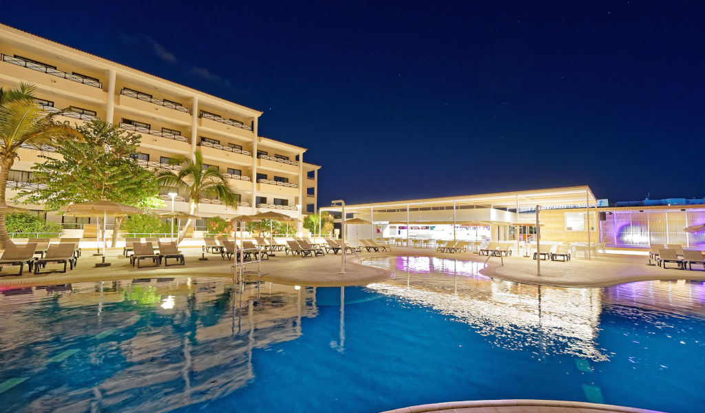Outdoor pool and illuminated hotel in Tenerife at night.