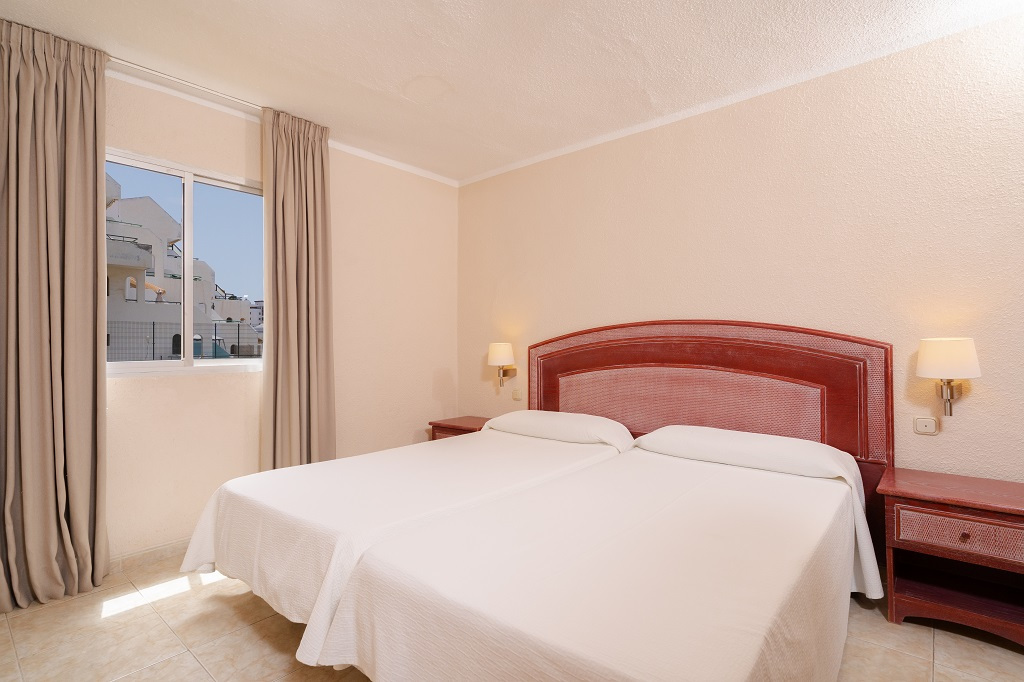 Two single beds in a hotel room with a window view in Tenerife.