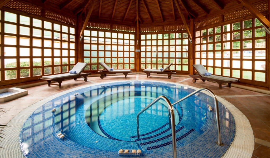 Indoor hot tub with wooden loungers in Tenerife spa.