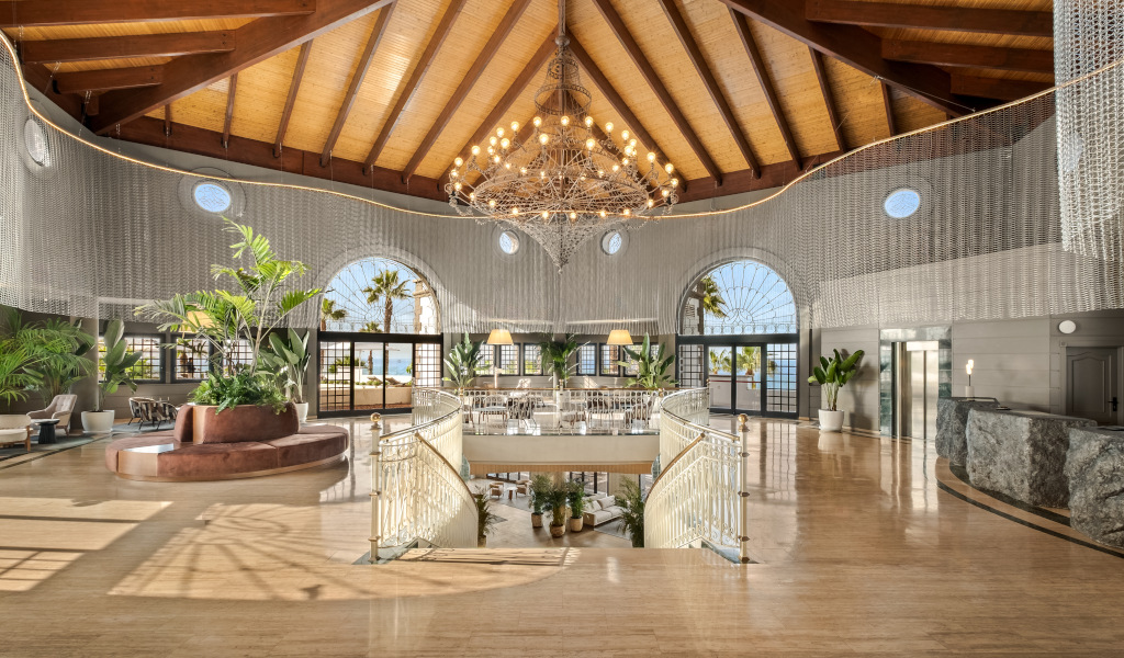 Spacious hotel lobby in Tenerife with plants and large chandelier.