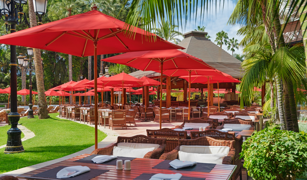 Outdoor restaurant seating with red umbrellas in Santa Cruz de Tenerife.