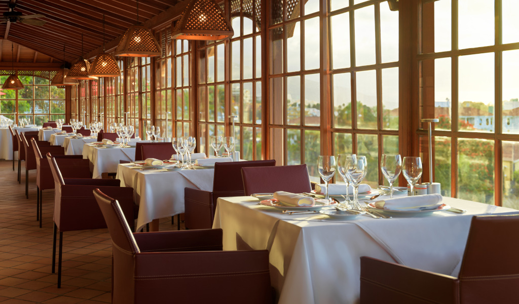 Dining tables set with white tablecloths and glassware in a Tenerife restaurant.