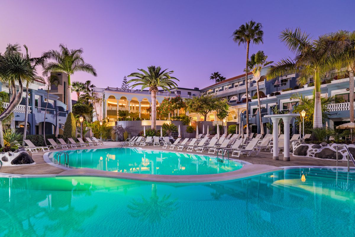Outdoor pool with palm trees and lounge chairs at a resort in Tenerife.