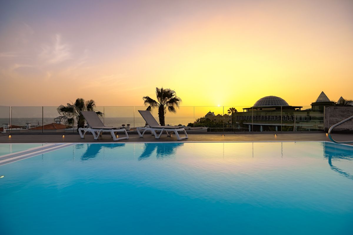 Sunset over a rooftop pool with lounge chairs in Tenerife.