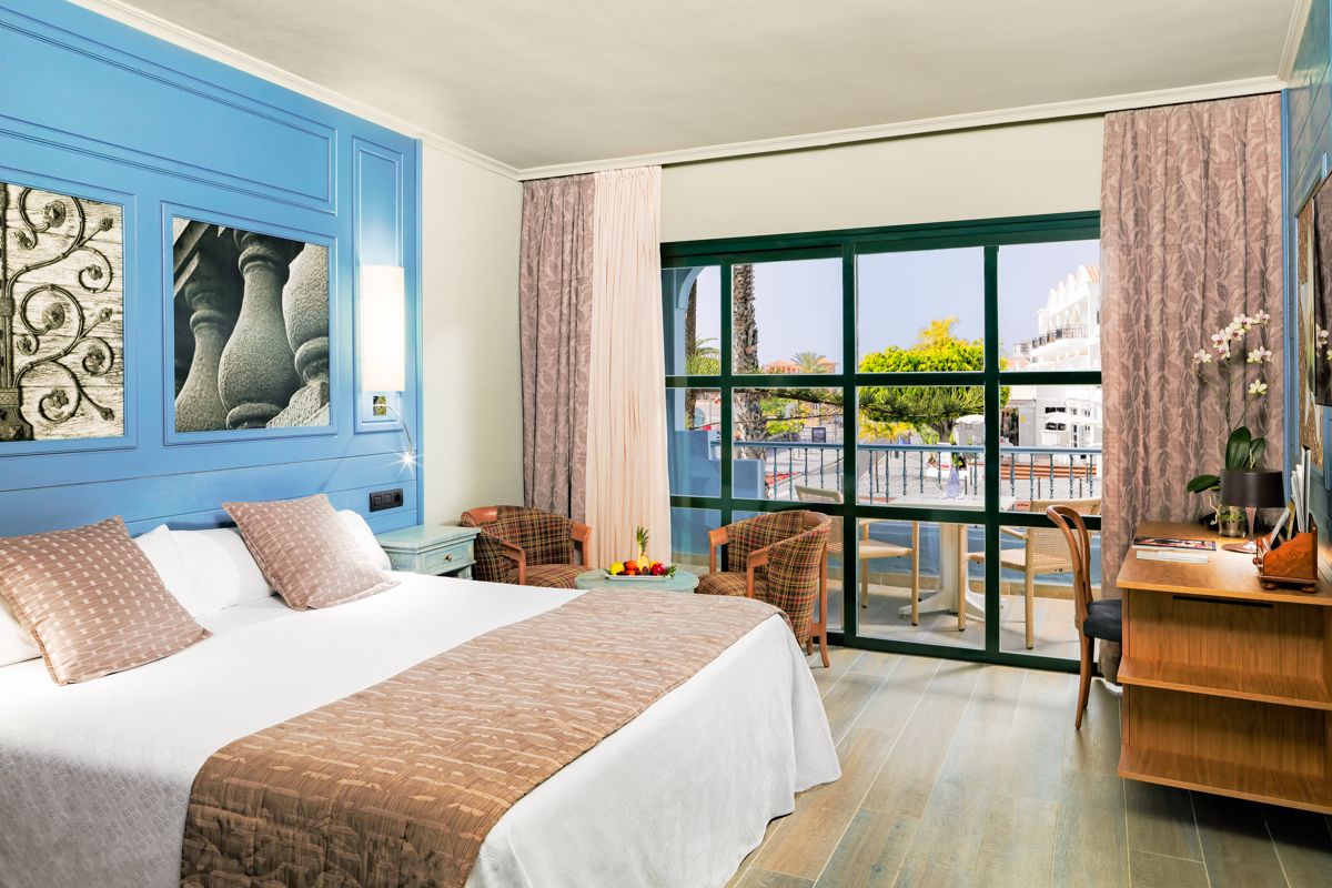 Hotel room with a double bed, armchairs, and balcony view in Tenerife.