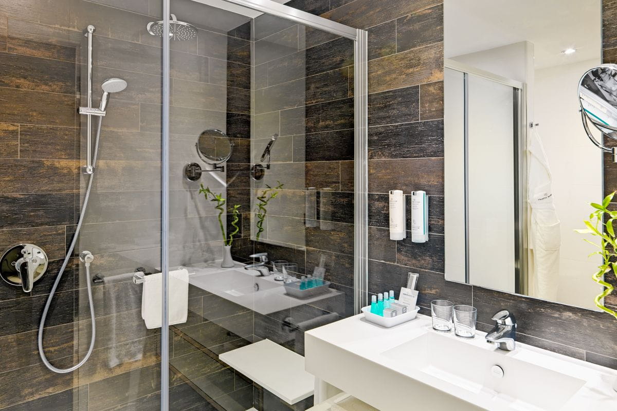Bathroom with glass shower, white sink, toiletries, and plants in Tenerife.