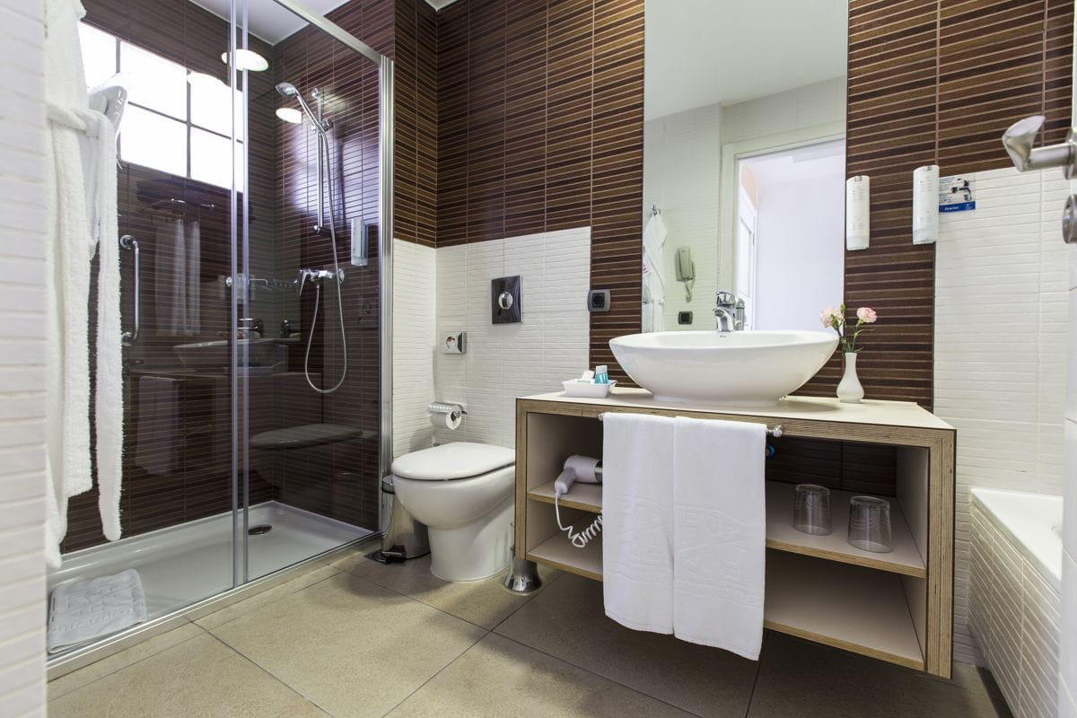 Bathroom with glass shower, toilet, and sink in a Tenerife hotel.