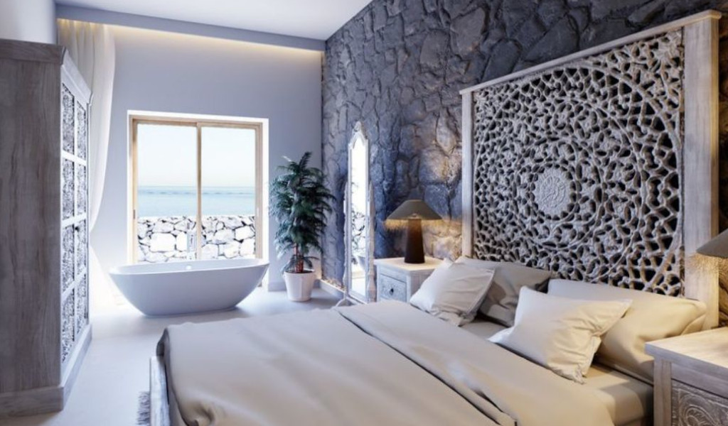 Luxurious bedroom with ornate headboard, ocean view, and bathtub in Tenerife.