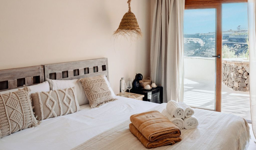 Bedroom with towels on bed, ocean view through glass doors in Tenerife.