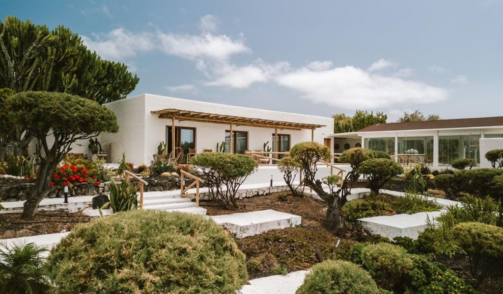 Modern house with garden and patio in Tenerife, featuring white walls and trees.
