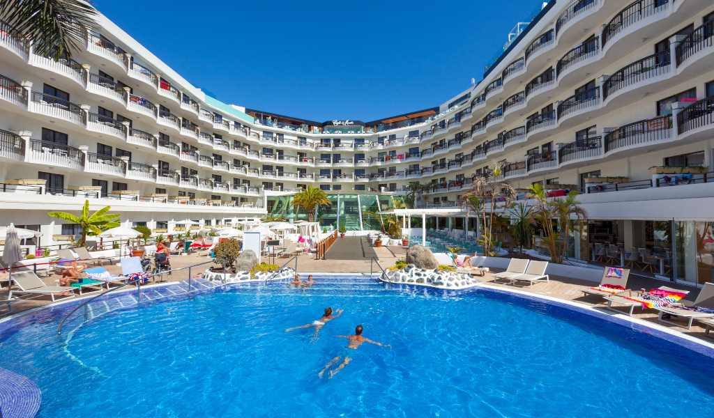 Outdoor pool area with two people swimming at a Tenerife hotel resort.