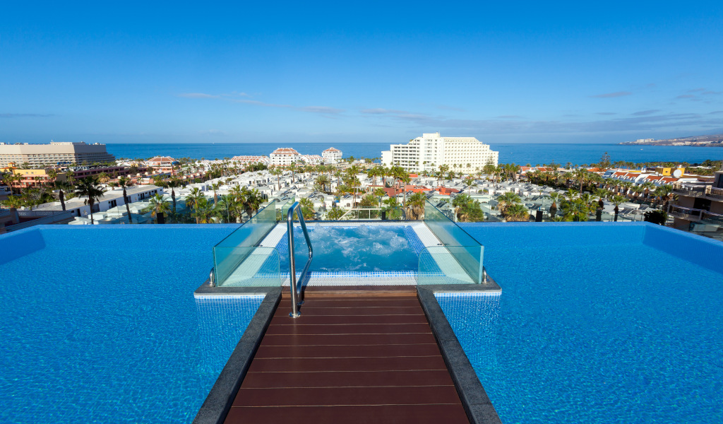 Rooftop pool with views of Costa Adeje, Tenerife, and the ocean backdrop.
