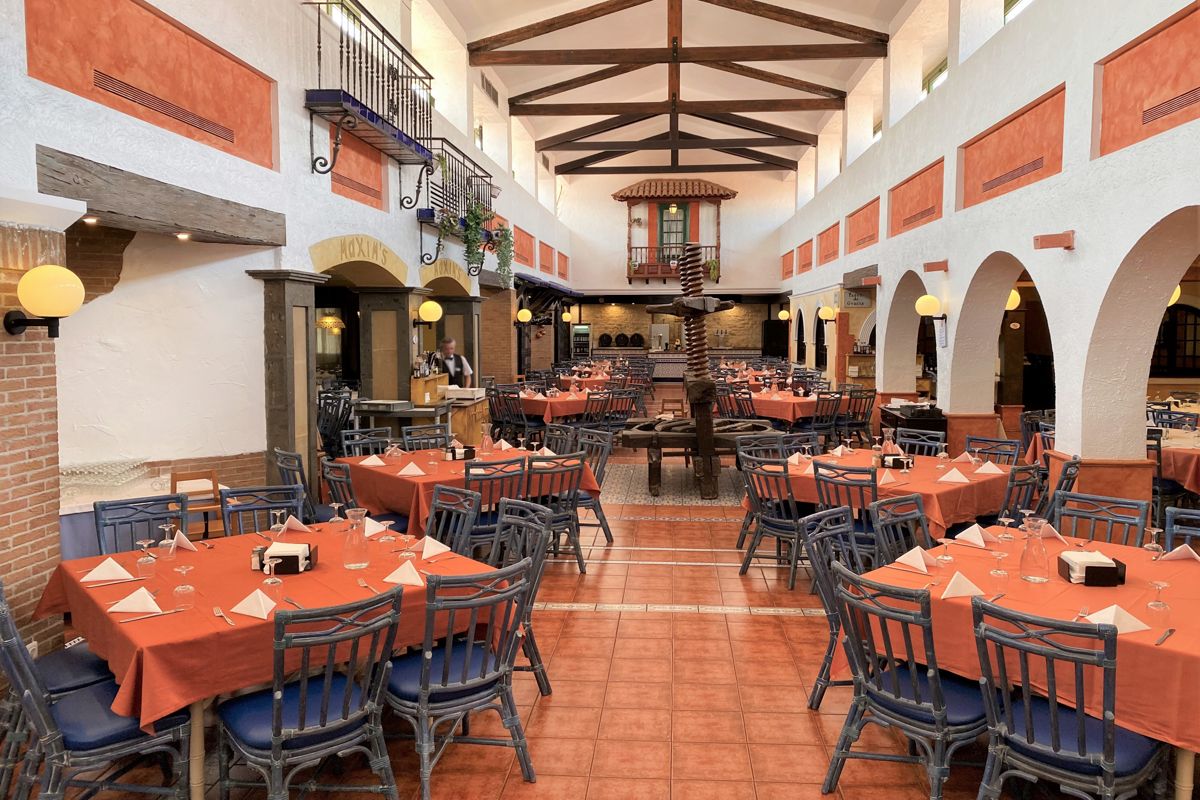 Dining area with tables, chairs, and orange tablecloths at a restaurant in Tenerife.