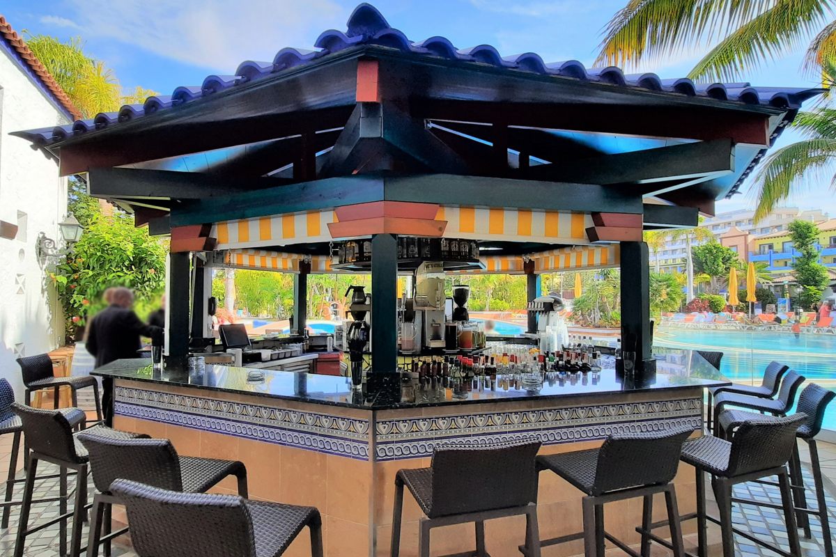 Poolside bar with stools and drinks, surrounded by palm trees in Tenerife.