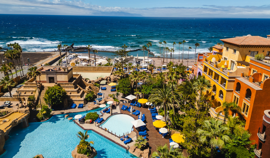 Pool and beach view from a hotel in Tenerife with ocean in the background.