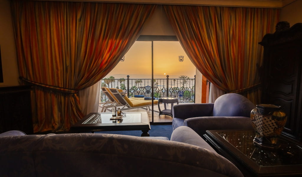 Sunset view from a Tenerife hotel room with balcony and armchairs.