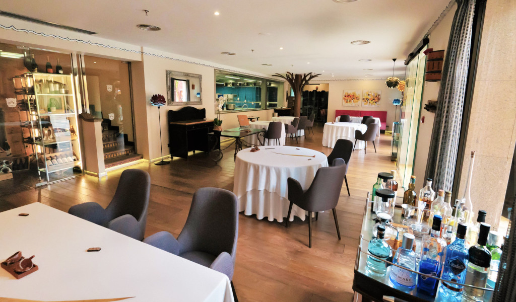 Elegant dining area with round tables and chairs, bottles on a cart in Tenerife restaurant.