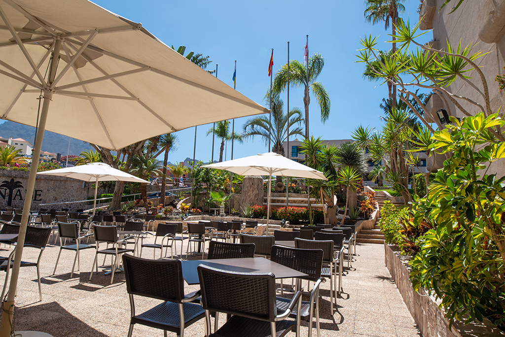 Outdoor seating area with tables, chairs, and umbrellas in Tenerife.