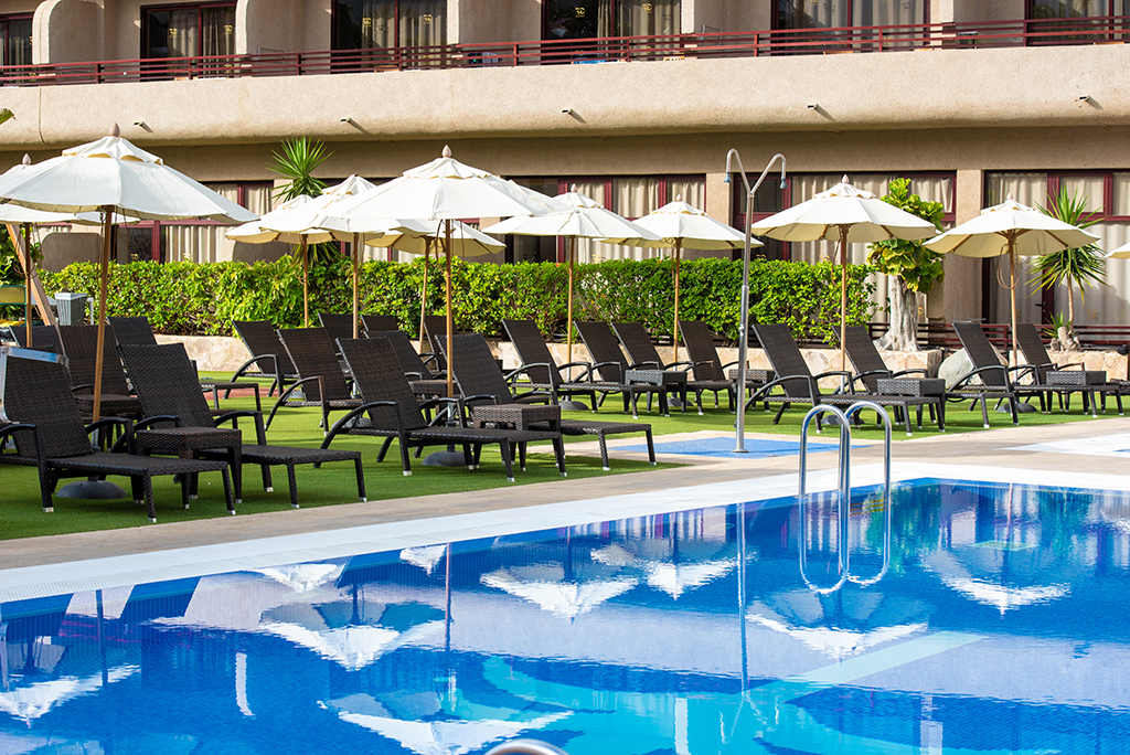 Sun loungers and umbrellas by a pool in a Tenerife hotel.