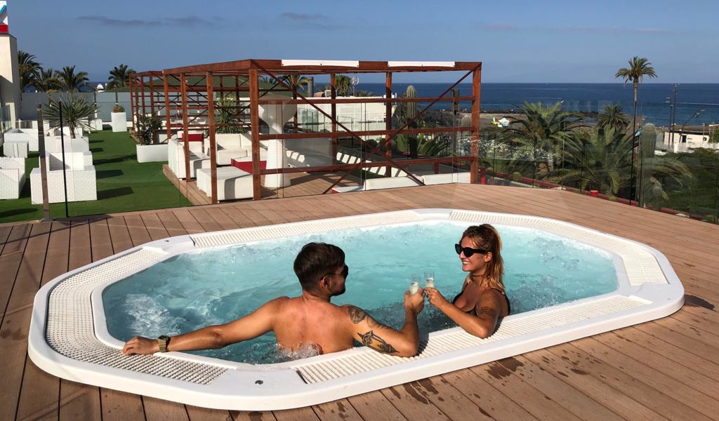 Couple in a Jacuzzi with ocean view in Tenerife resort.