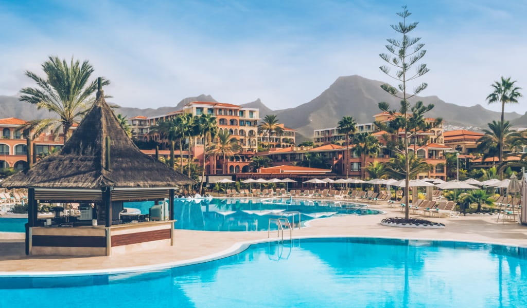 Pool and palm trees with Costa Adeje buildings in the background, Tenerife.