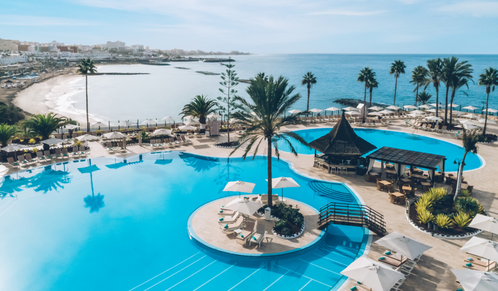 Poolside view at a Tenerife resort overlooking the ocean and beach.