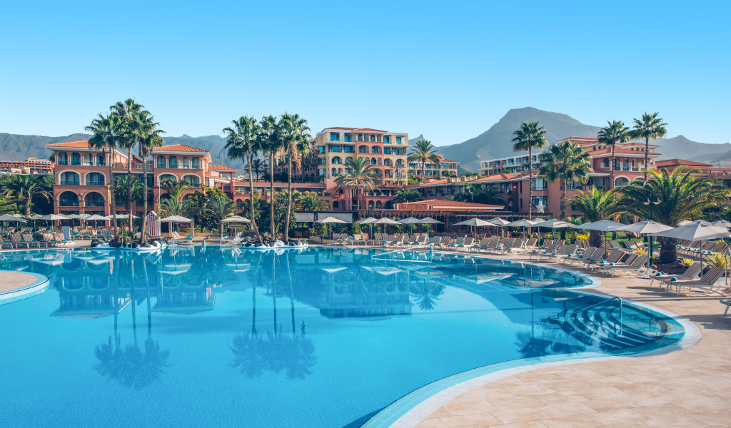 Resort pool area with palm trees and sun loungers in Tenerife.