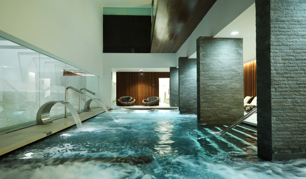 Indoor spa pool with waterfalls and stone pillars in a Tenerife resort.