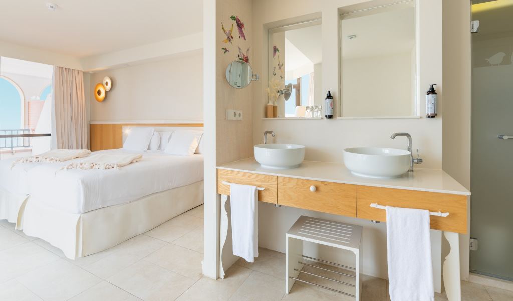 Hotel room in Tenerife with a bed, balcony view, and a bathroom sink area.