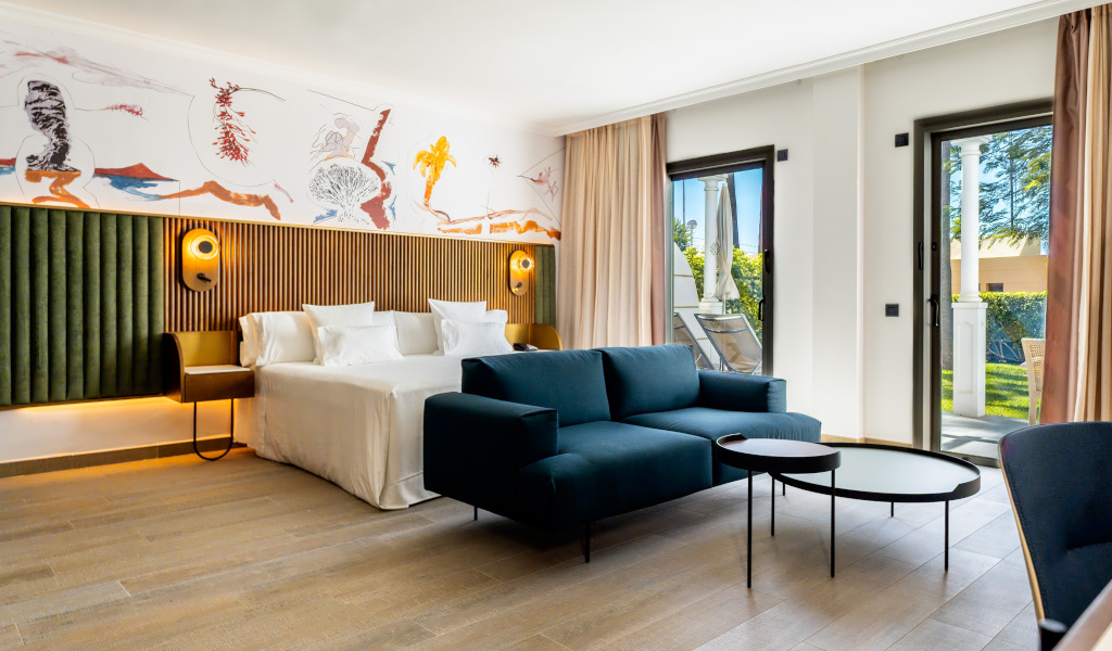 Modern hotel room with double bed, sofa, coffee table, and balcony access in Tenerife.