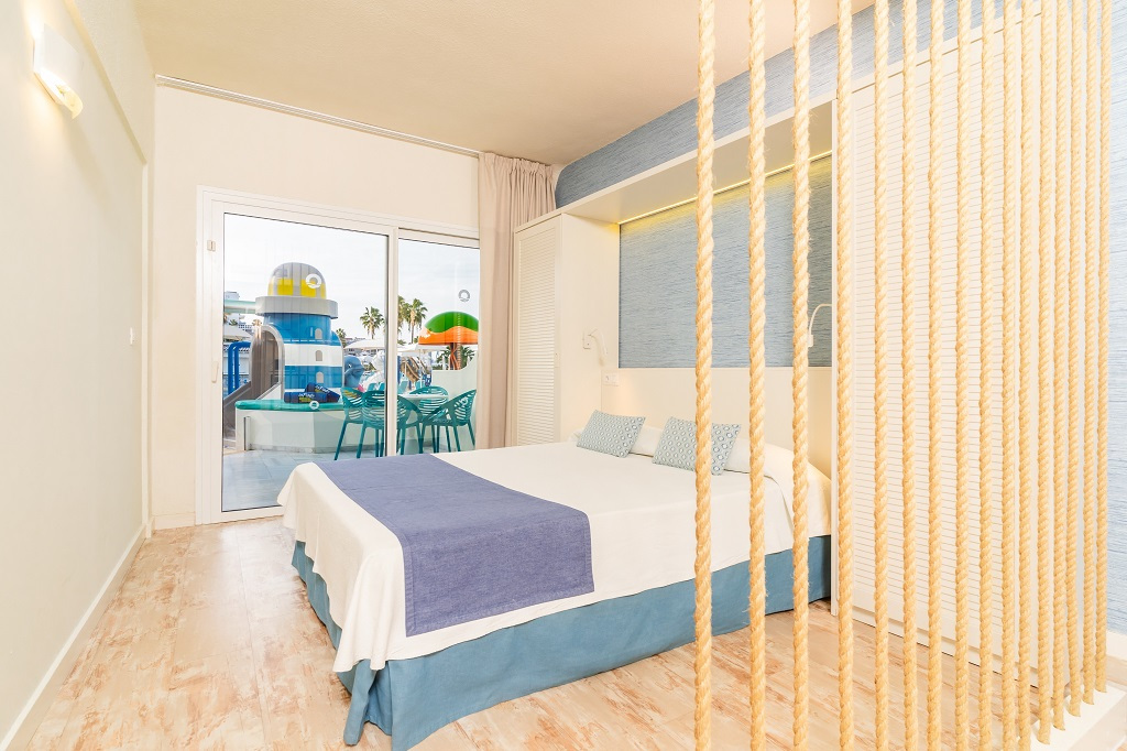 Hotel room with a bed, rope divider, and terrace overlooking a water park in Tenerife.