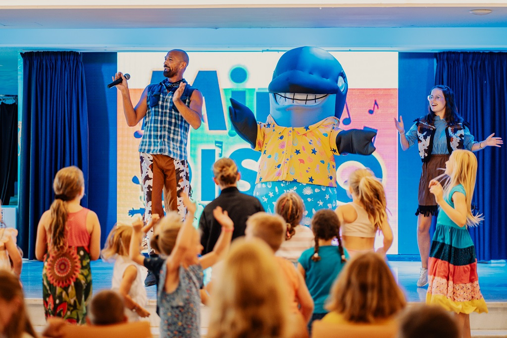 Kids enjoying a show with performers and a dolphin mascot in Tenerife.