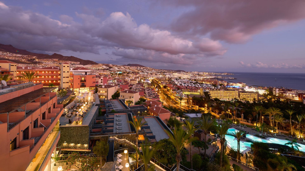 Aerial view of Costa Adeje in Tenerife at dusk with illuminated buildings and ocean.